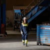 A Stena Metall Group employee wearing protective gear walks past a recycling container in a Stena facility.