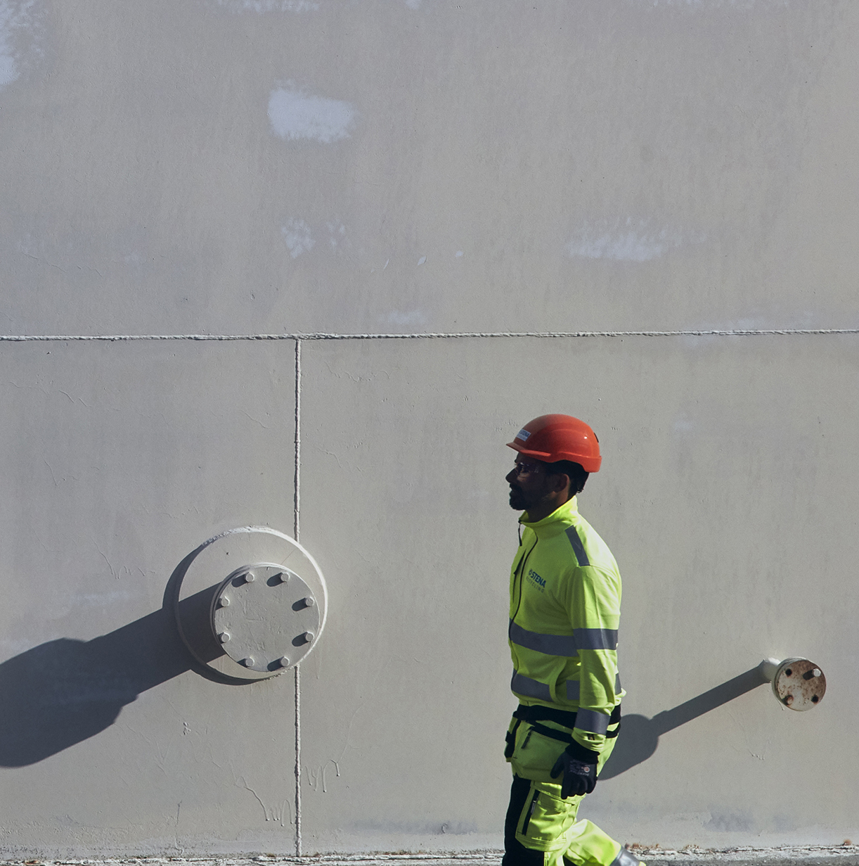 A Stena Metall Group employee in hi-vis, protective gear walks past a Stena facility.