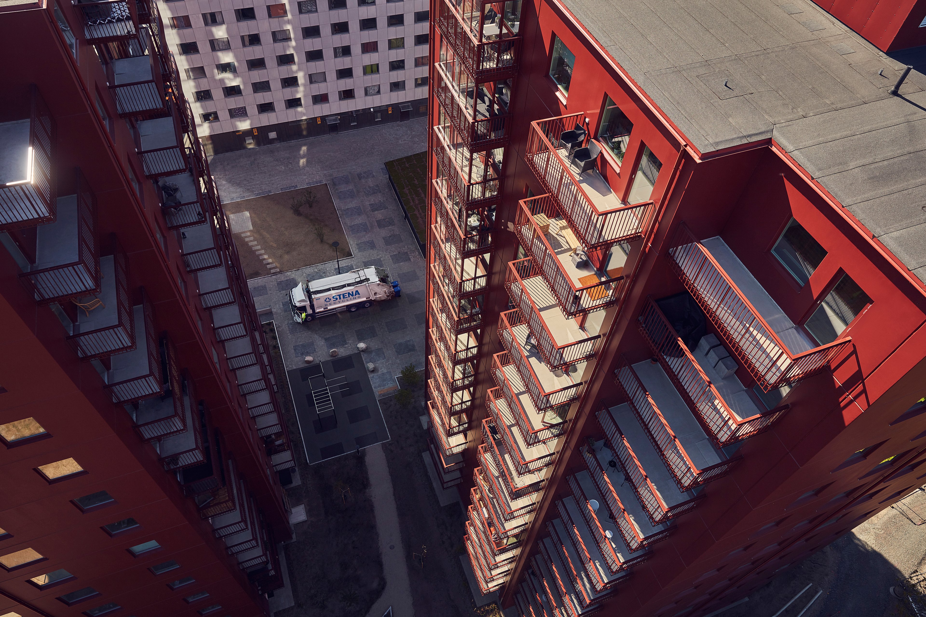 Bird’s eye view of a white Stena Recycling lorry collecting waste in a courtyard between tall residential buildings.