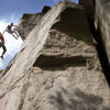 Two climbers scale a rock face – one holds the other in mid-air by the hand.