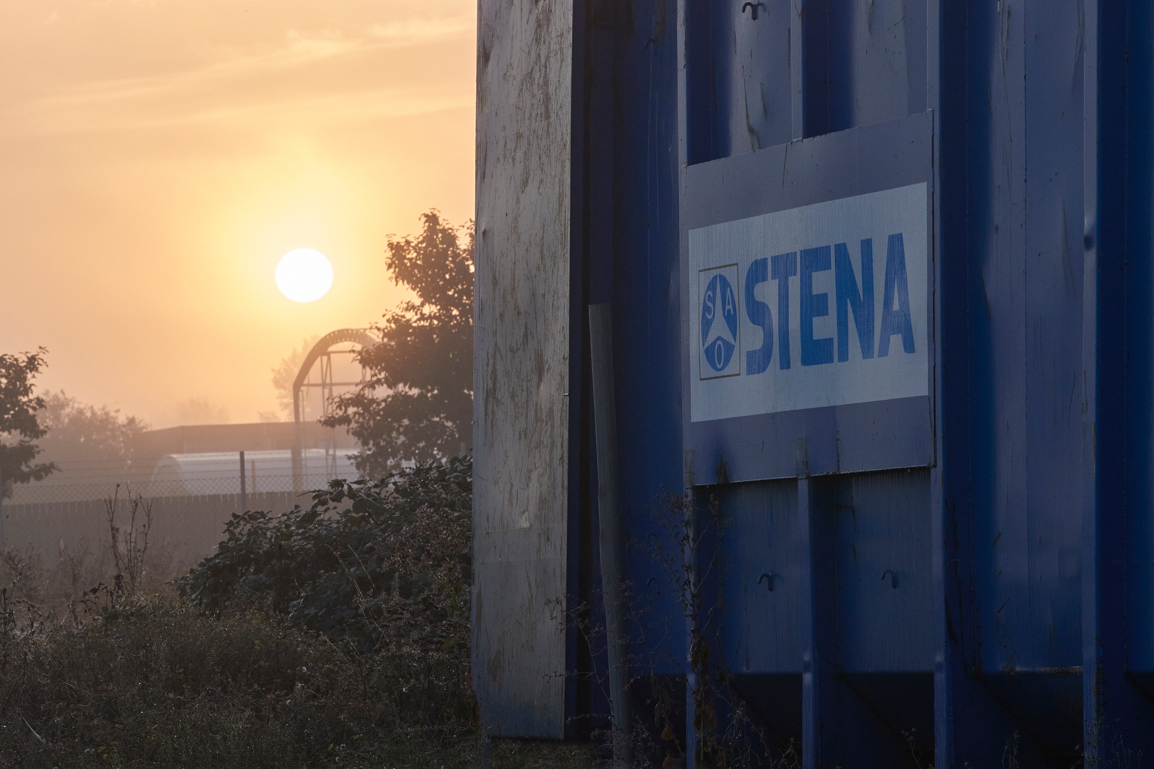 The sun sets over a Stena Metall Group facility with the Stena logo in the foreground.