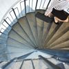 A female Stena Metall Group employee climbs a spiral staircase in a modern office environment.