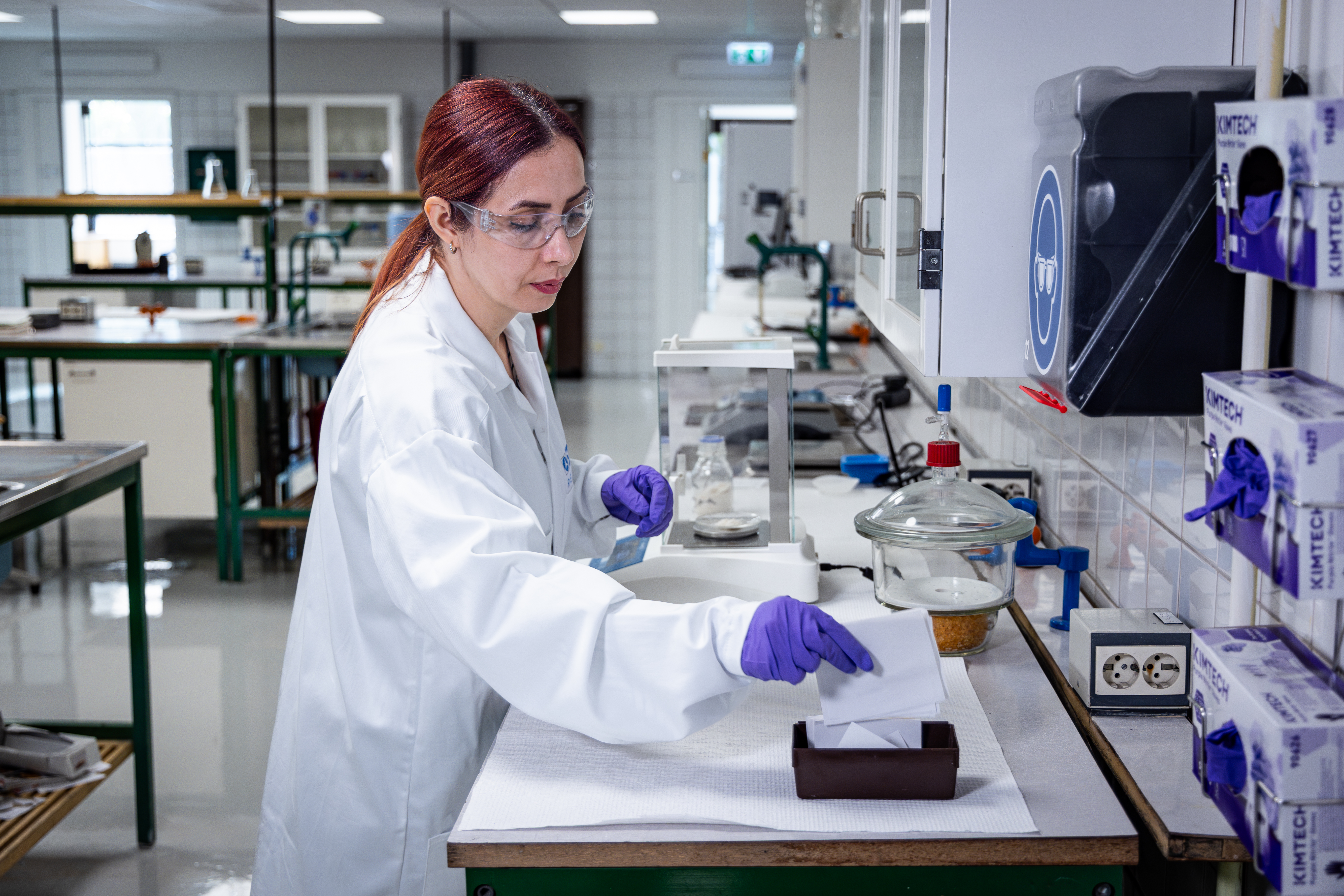 Samira Akbari, dressed in a lab coat, is analyzing composite material and how to best recycle it.