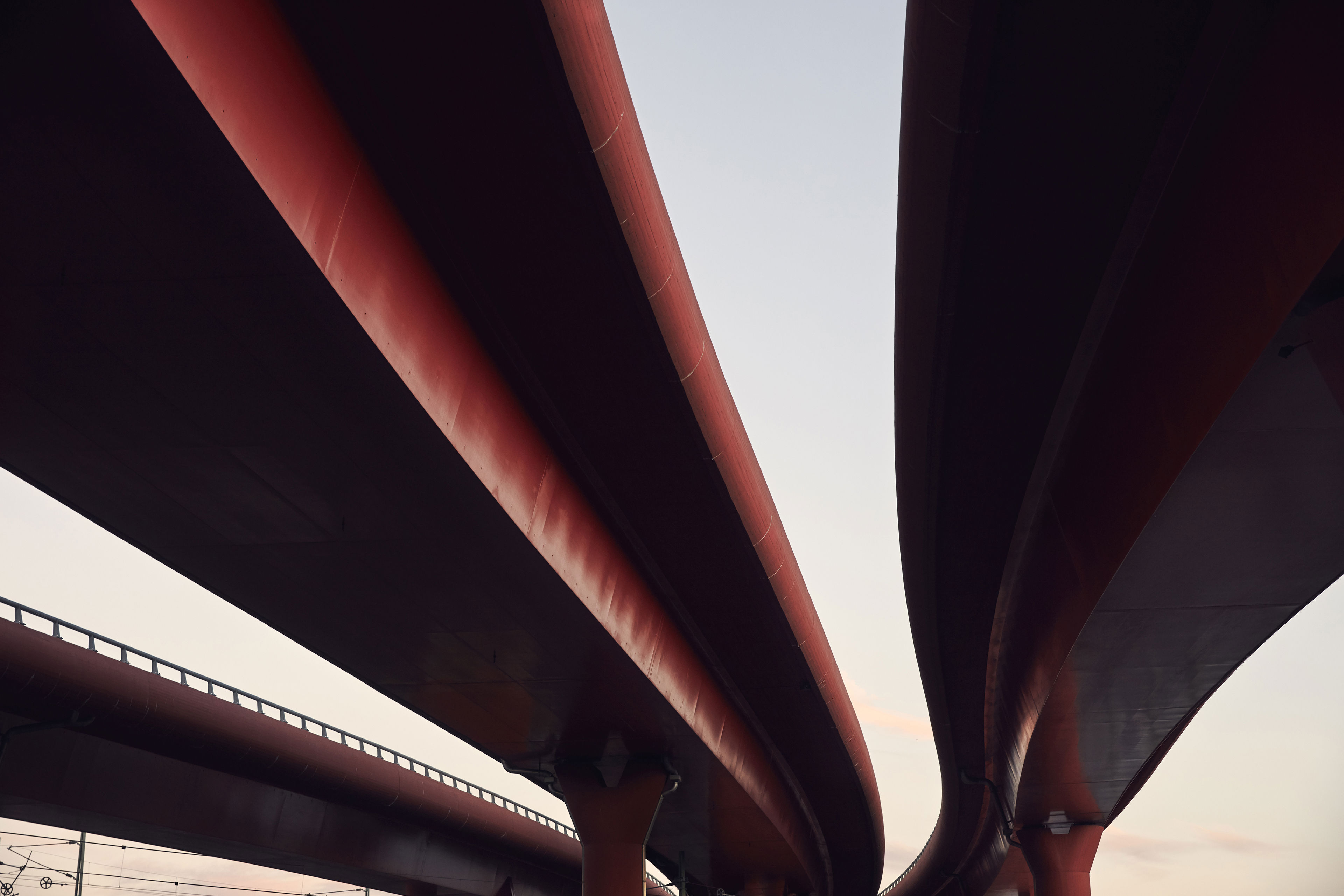 Three red motorway flyovers passing over a railway line.