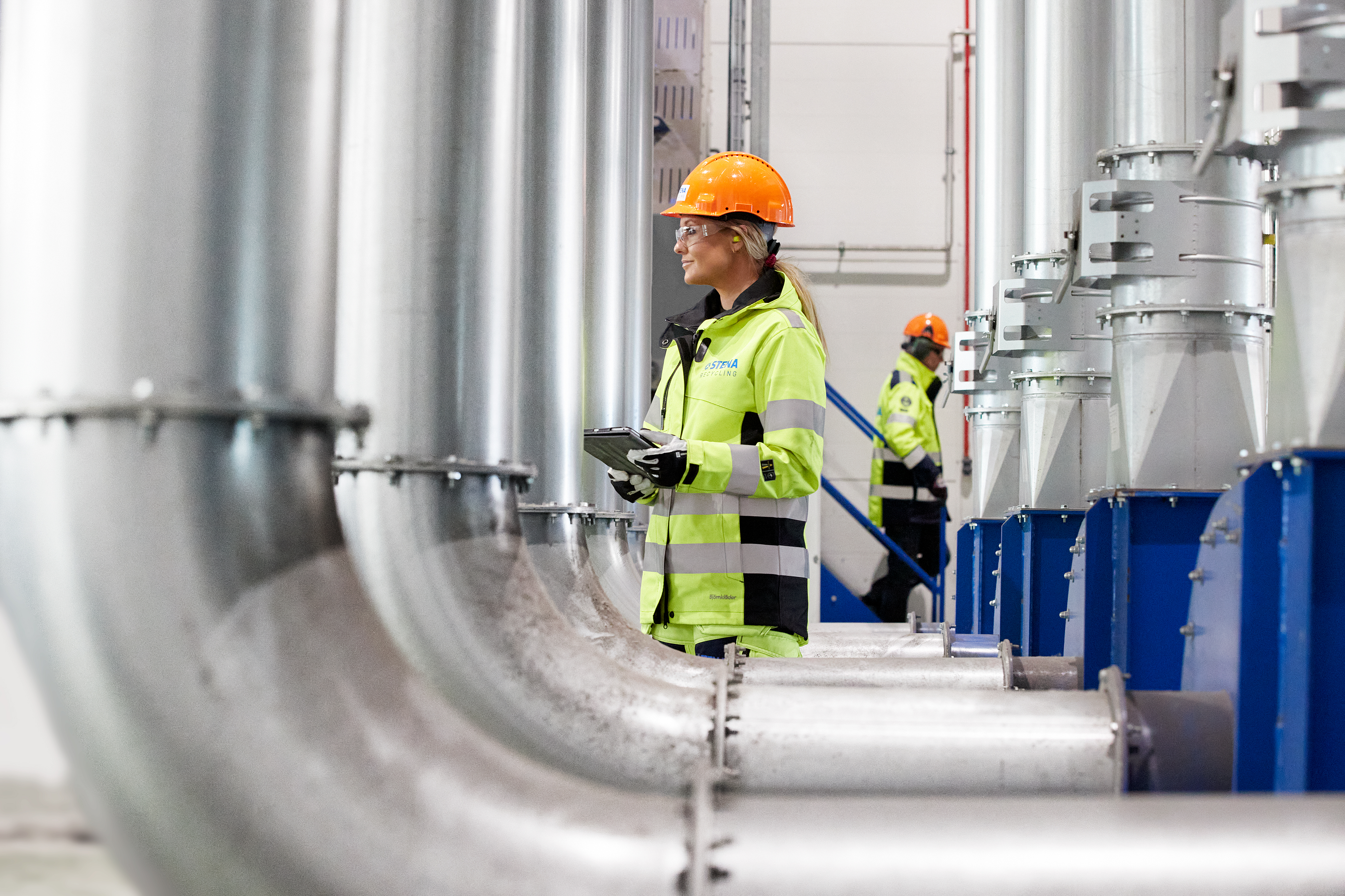 A female Stena Metall Group employee at work in a Stena facility wearing hi-vis protective gear.